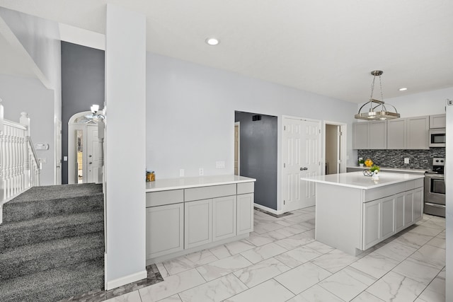 kitchen with white microwave, marble finish floor, stainless steel electric range, and arched walkways