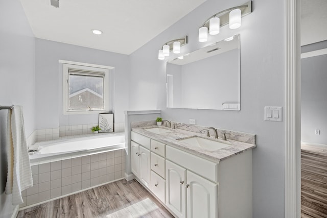 bathroom featuring a bath, wood finished floors, visible vents, and a sink