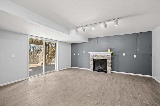 unfurnished living room featuring baseboards, a textured ceiling, wood finished floors, and a fireplace