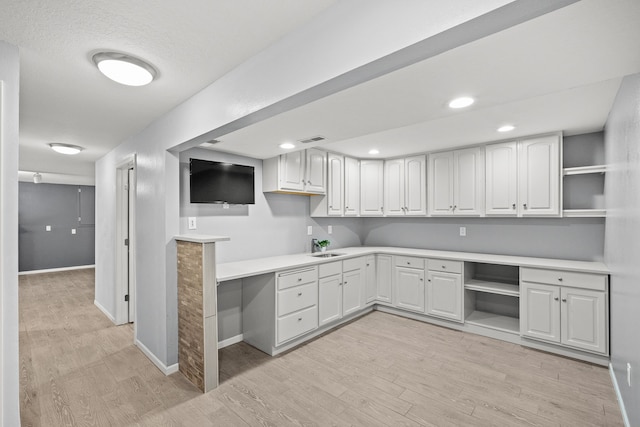 kitchen featuring light wood-type flooring, visible vents, open shelves, a sink, and built in study area