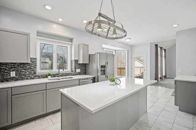 kitchen featuring a sink, gray cabinetry, light countertops, stainless steel appliances, and marble finish floor