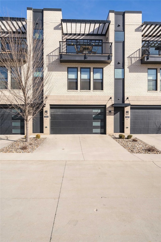 townhome / multi-family property featuring brick siding, driveway, and an attached garage