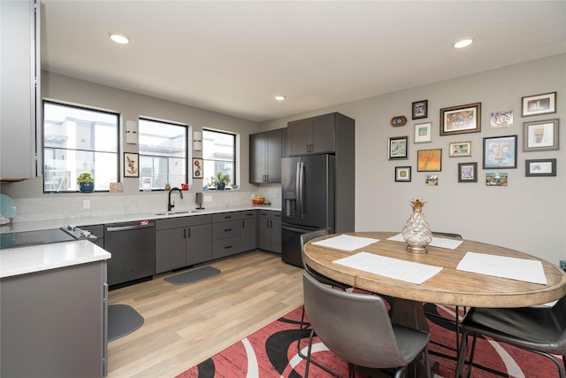 kitchen featuring a sink, gray cabinetry, light wood-style floors, stainless steel dishwasher, and fridge with ice dispenser