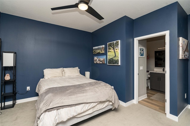 bedroom with light carpet, ceiling fan, ensuite bath, and baseboards