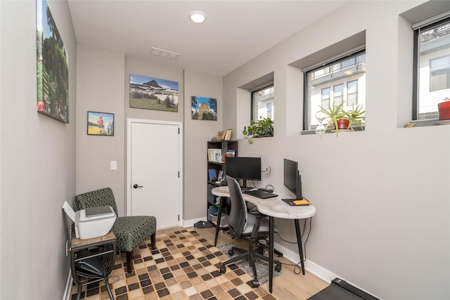 office space with visible vents, light wood-style floors, and baseboards