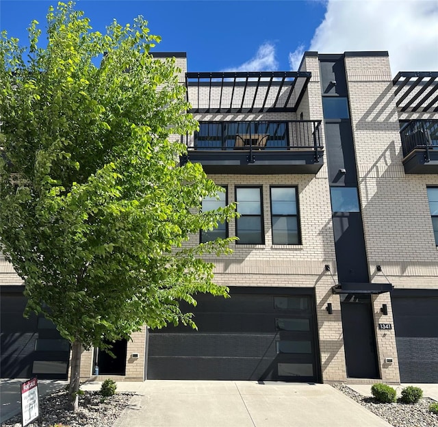 1343 Keosauqua Way, Des Moines, IA 50309 - view of front of house with brick siding, a balcony, driveway, and an attached garage