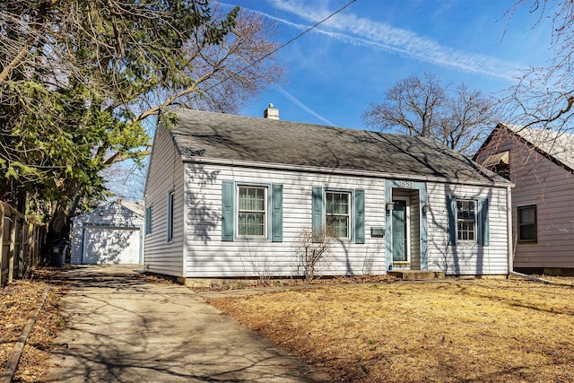 view of front facade with an outbuilding, fence, driveway, a chimney, and a detached garage