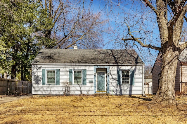 view of front of home with a shingled roof, fence, and a chimney