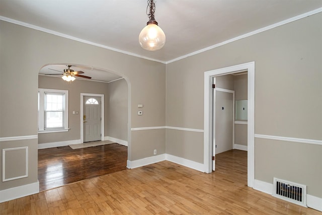 spare room featuring visible vents, crown molding, baseboards, hardwood / wood-style floors, and arched walkways