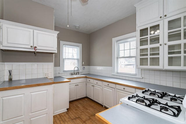 kitchen featuring glass insert cabinets, white cabinetry, light wood-type flooring, and a sink