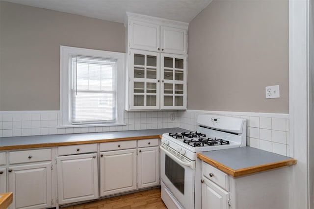 kitchen with white cabinetry, glass insert cabinets, light countertops, and white gas range oven