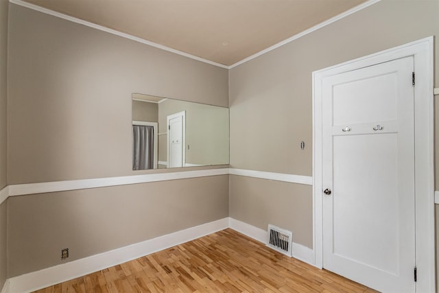 spare room with baseboards, wood finished floors, visible vents, and ornamental molding