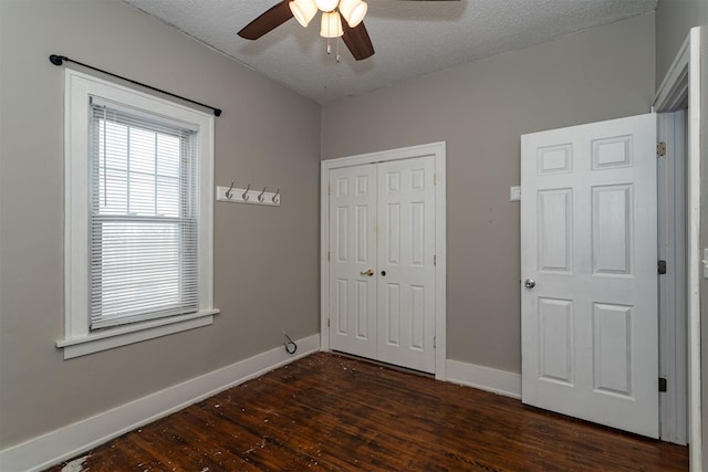 unfurnished bedroom with a ceiling fan, dark wood-style floors, baseboards, a closet, and a textured ceiling