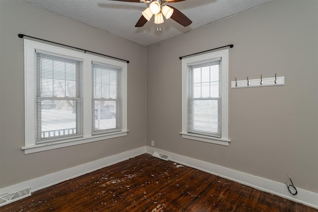 unfurnished room featuring ceiling fan, visible vents, baseboards, and dark wood finished floors