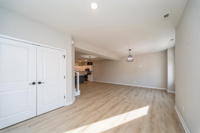 unfurnished living room featuring visible vents, light wood-style flooring, recessed lighting, baseboards, and a chandelier