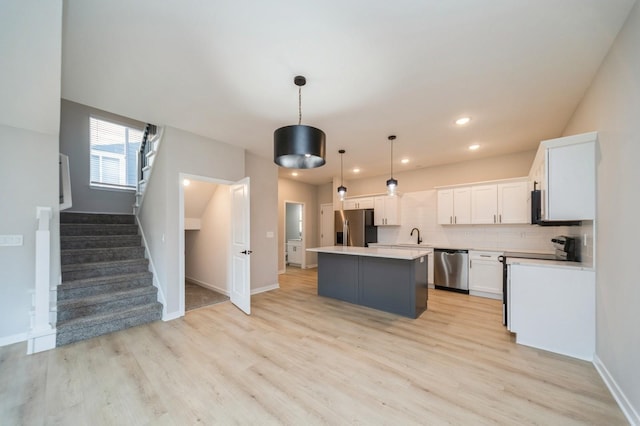 kitchen featuring a kitchen island, stainless steel appliances, light wood-style floors, white cabinets, and decorative backsplash