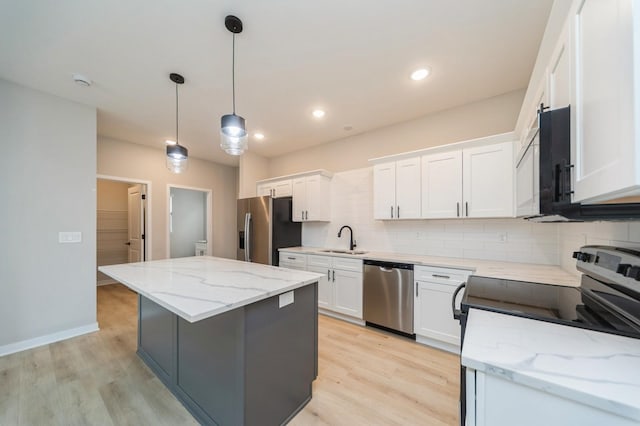 kitchen with tasteful backsplash, a kitchen island, light wood-style flooring, stainless steel appliances, and a sink