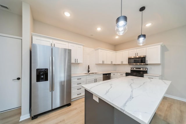 kitchen featuring a sink, decorative backsplash, light wood finished floors, and stainless steel appliances