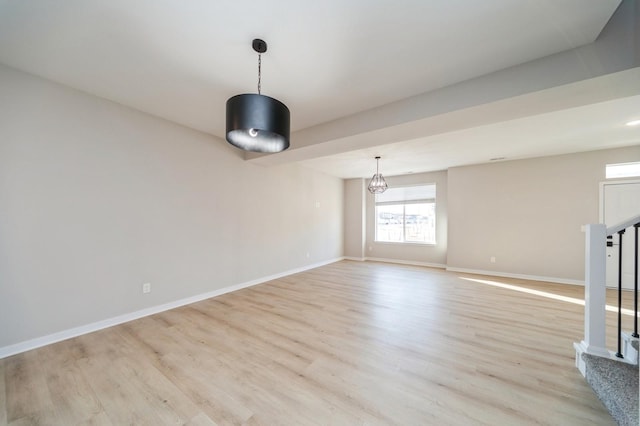 unfurnished room featuring light wood finished floors, stairs, and baseboards