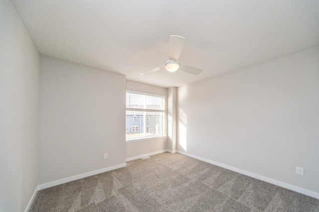 carpeted empty room with a ceiling fan and baseboards