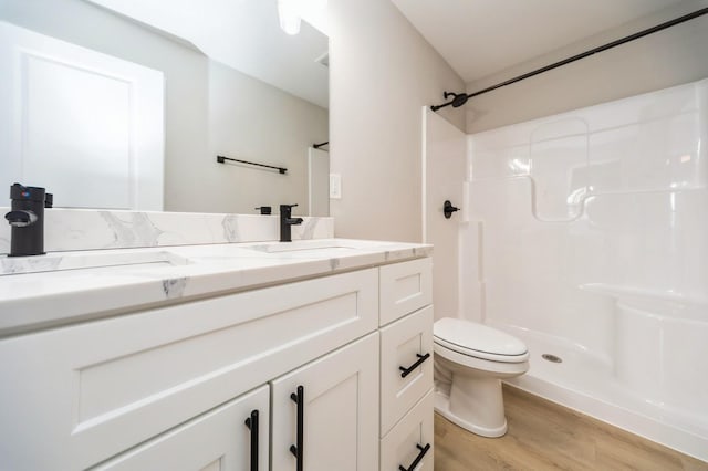 bathroom with a shower, toilet, wood finished floors, and vanity