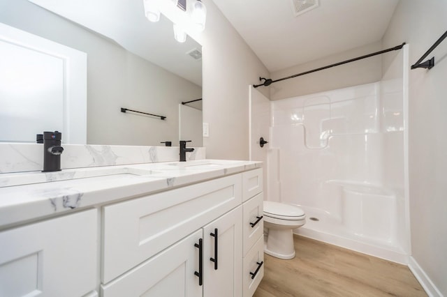 bathroom featuring vanity, wood finished floors, visible vents, walk in shower, and toilet