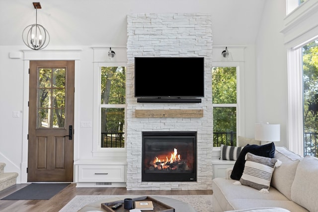 living area featuring visible vents, wood finished floors, stairway, a fireplace, and a chandelier