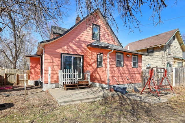 rear view of house featuring a patio, fence, and a chimney