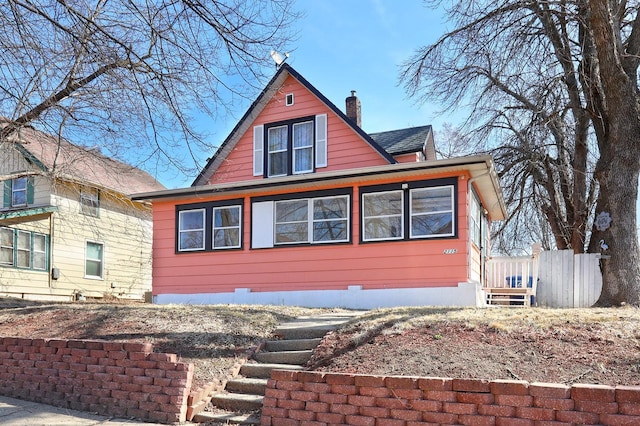 view of front facade with roof with shingles and a chimney