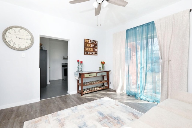 bedroom featuring ceiling fan, baseboards, multiple windows, and wood finished floors