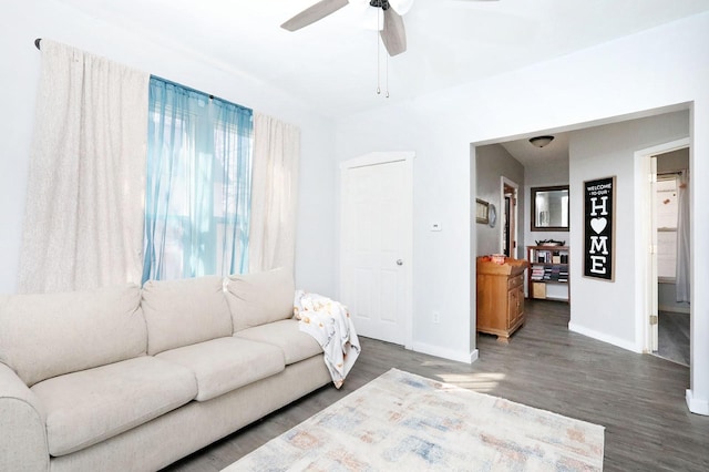 living area featuring a ceiling fan, baseboards, and wood finished floors