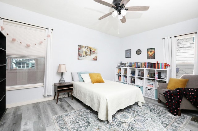 bedroom with multiple windows, ceiling fan, and wood finished floors