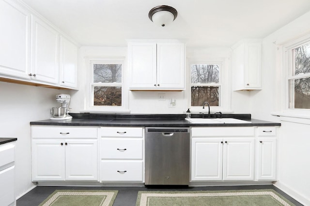 kitchen featuring dishwasher, dark countertops, white cabinetry, and a sink