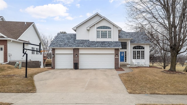 traditional-style home featuring brick siding, a front lawn, concrete driveway, and roof with shingles