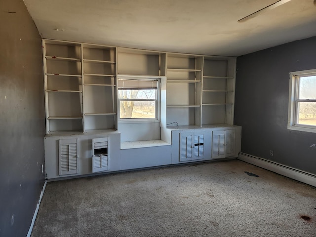 unfurnished living room featuring a baseboard heating unit, baseboards, and carpet