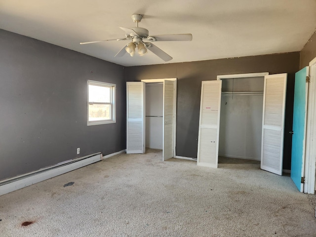 unfurnished bedroom featuring a baseboard radiator, carpet floors, two closets, and ceiling fan