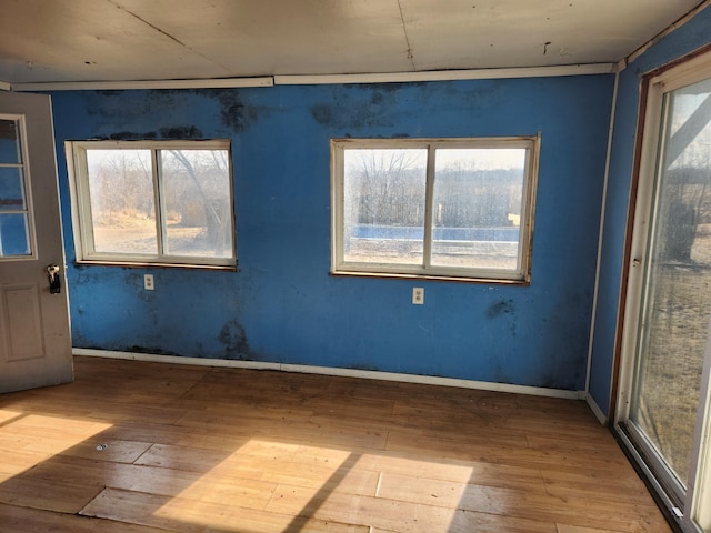 unfurnished room featuring baseboards, plenty of natural light, and hardwood / wood-style flooring