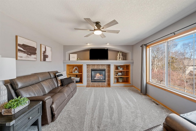 living area with baseboards, a tile fireplace, a textured ceiling, and carpet