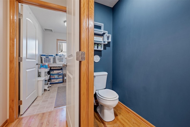 bathroom with visible vents, toilet, and wood finished floors