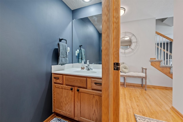 bathroom with baseboards, a textured ceiling, wood finished floors, and vanity