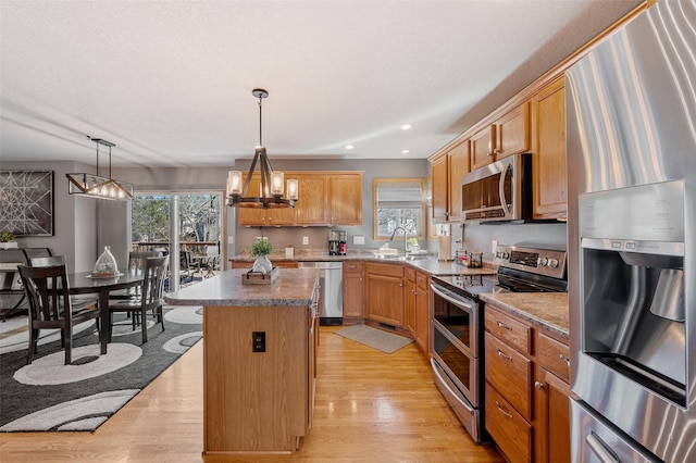 kitchen featuring a wealth of natural light, stainless steel appliances, a center island, and light wood finished floors