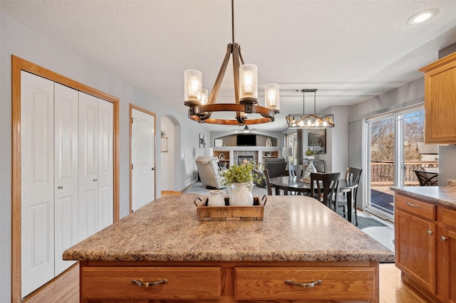 kitchen featuring a kitchen island, open floor plan, pendant lighting, arched walkways, and a textured ceiling