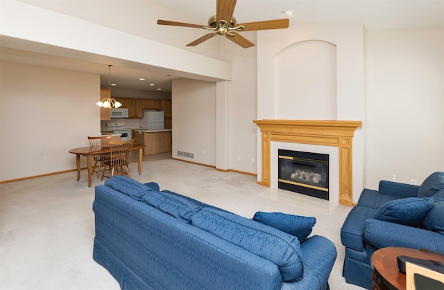 living room with visible vents, light carpet, baseboards, and a glass covered fireplace