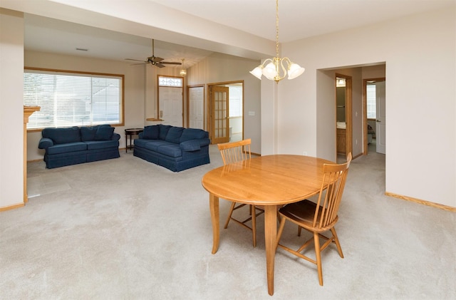 dining space with light colored carpet, ceiling fan with notable chandelier, and baseboards