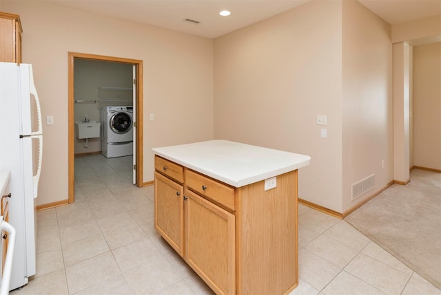 kitchen featuring washer / dryer, visible vents, freestanding refrigerator, and a sink