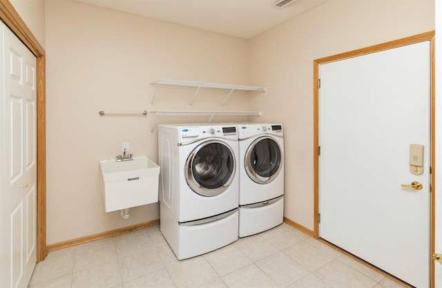 laundry room with laundry area, light tile patterned floors, baseboards, and independent washer and dryer