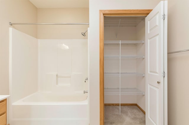 full bathroom with tub / shower combination, vanity, a walk in closet, and baseboards