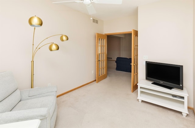 living room with visible vents, baseboards, light colored carpet, and a ceiling fan