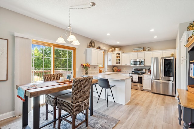 dining area with light wood finished floors, a chandelier, recessed lighting, and baseboards