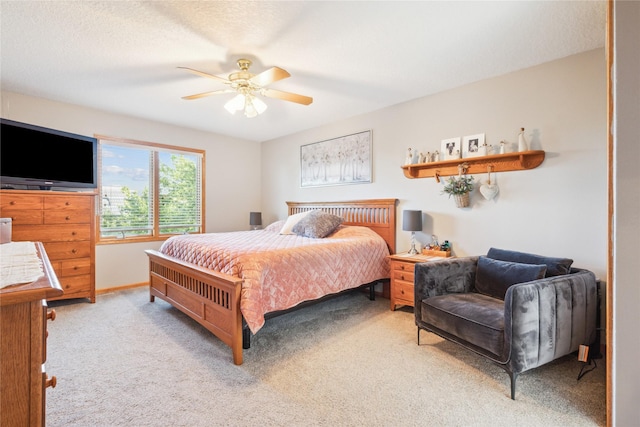 bedroom featuring baseboards, light colored carpet, a ceiling fan, and a textured ceiling